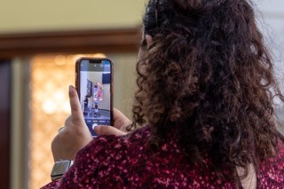 Over-the-shoulder shot of woman taking a photo with her phone.